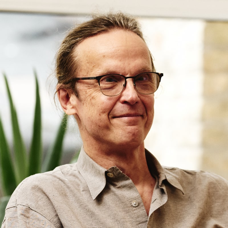 Alex Blumentals, close portrait, in a light shirt and glasses